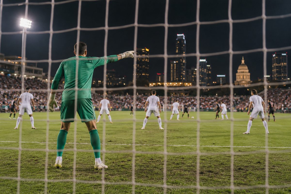 A goalkeeper organising a defensive line during a night match