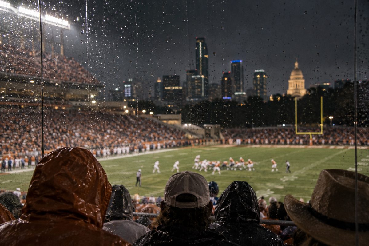 A night football fixture seen through a rain-specked barrier